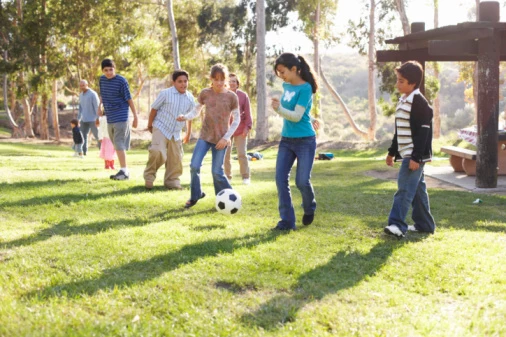 Children (9-14) playing soccer in park